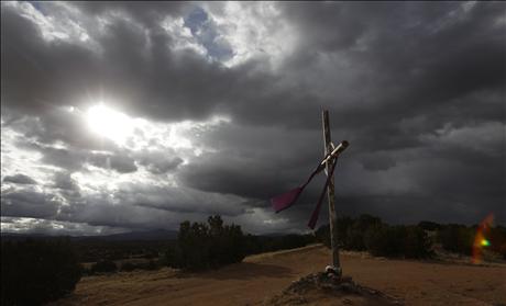 A cross is seen on the hill as the sun rises on Easter morning in Chimayo