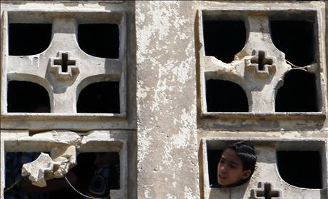 A Coptic Christian boy looks out of the Saint Mary Church which was set on fire during clashes between Muslims and Christians on Saturday in the heavily populated area of Imbaba in Cairo