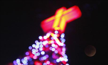 A total lunar eclipse is seen with a Christmas tree in foreground in Seoul