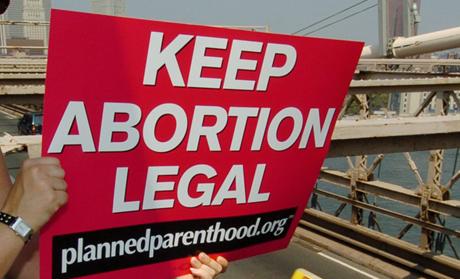 Planned Parenthood abortion rights protester signals Brooklyn Bridge traffic.