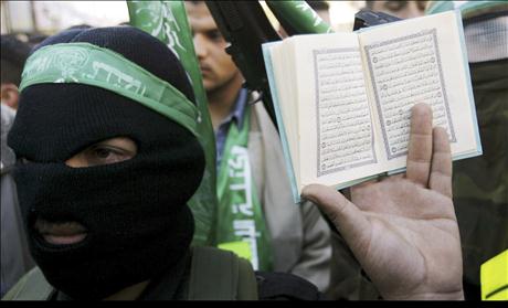 A Palestinian man holds a Koran as a members of the Islamic group Hamas look on during a protest in Nablus