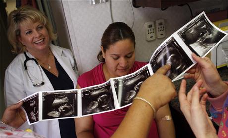 Nurse practitioner Gail Brown (L) an unidentified patient and other nurses look at a print out of an ultrasound from a prenatal exam at the Maternity Outreach Mobile in Phoenix