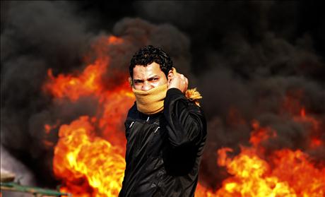 A protester stands in front of a burning barricade during a demonstration in Cairo