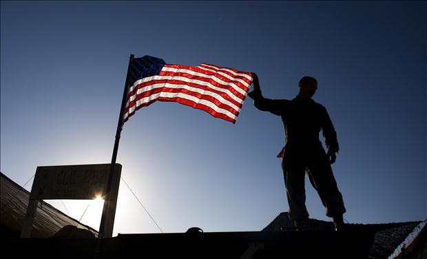 A U.S. Marine from 3rd Battalion 4th Marines, adjusts the U.S. flag on the top of his tent on base Delaram in Nimroz province