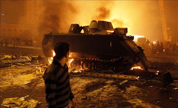 A protester looks at a burnt Egyptian Army armoured vehicle in downtown Cairo