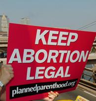 Planned Parenthood abortion rights protester signals Brooklyn Bridge traffic.